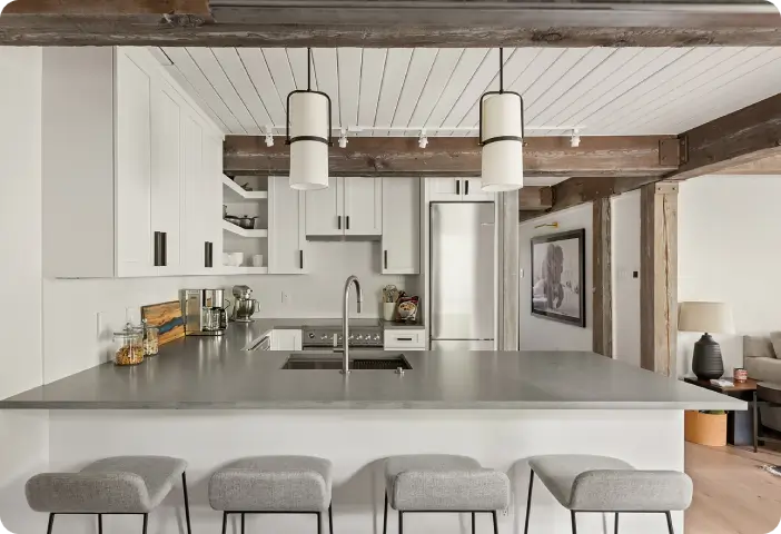 Modern-kitchen-with-white-cabinetry-gray-island-bar-stools-and-exposed-wood-beams Modern kitchen with white cabinetry, gray island, bar stools, and exposed wood beams