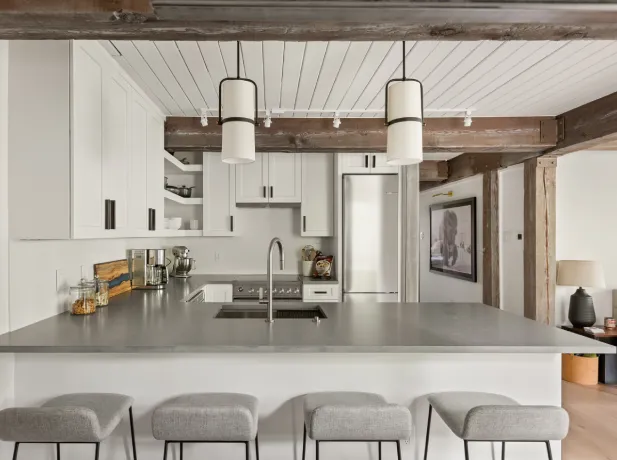 Modern sage green kitchen with marble backsplash, wood island, and snowy mountain view